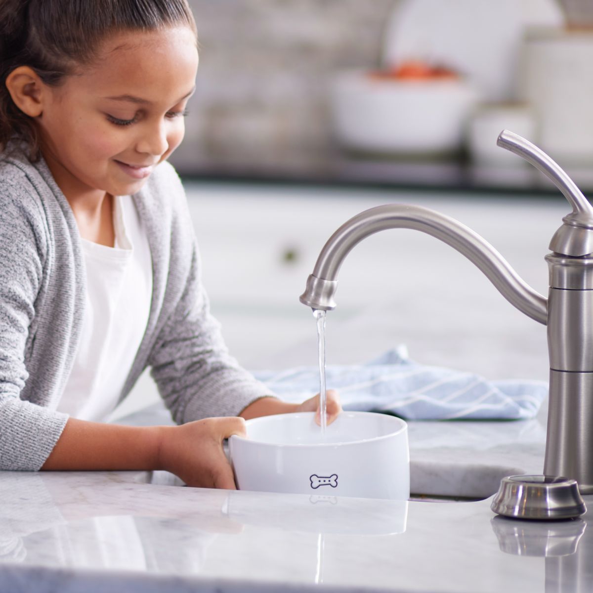 young girl collecting water into a dog bowl