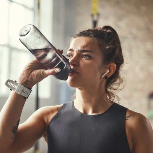 Woman drinking from bottled water after workout