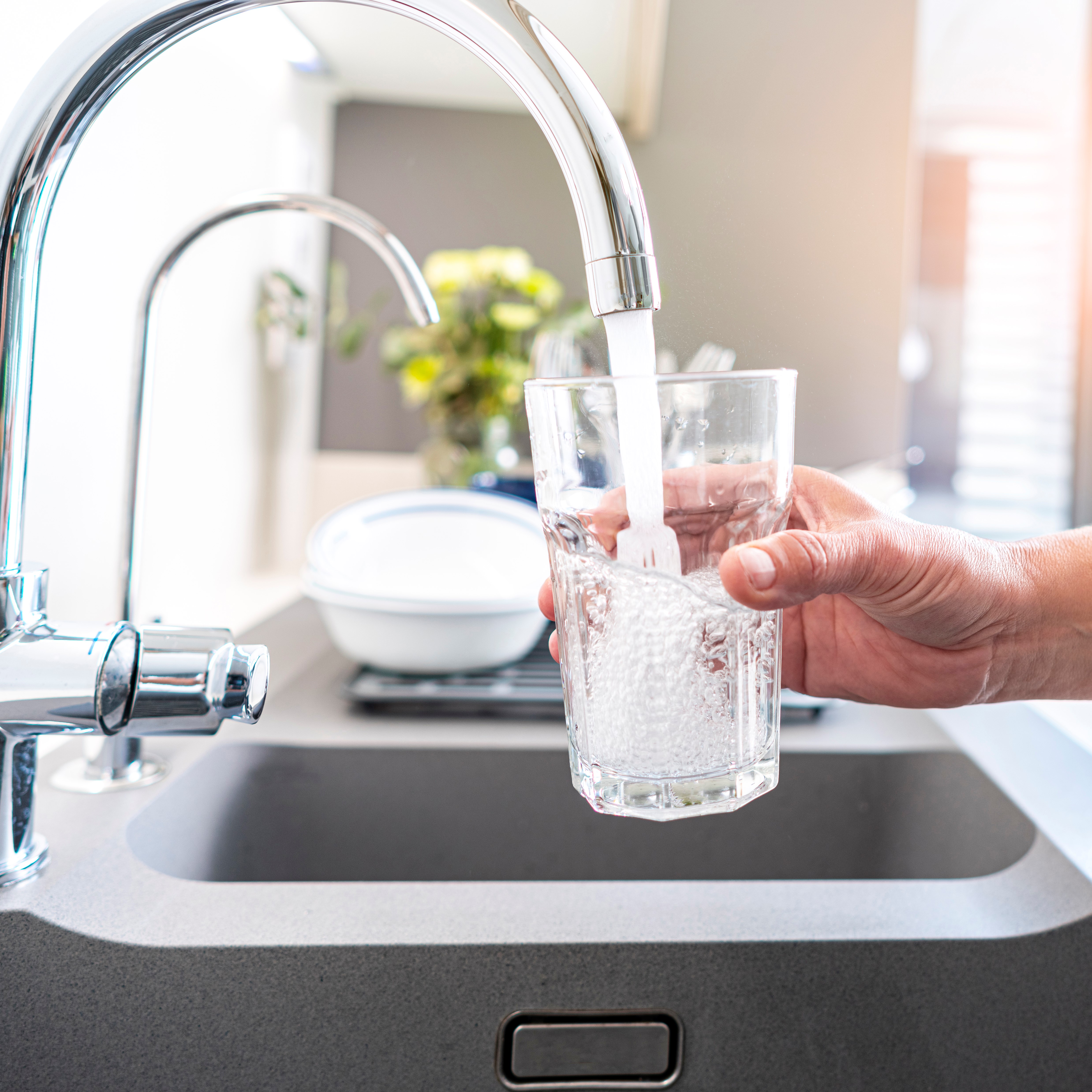 Close up of a woman hand filling a glass of water directly from the tap. High resolution 42Mp indoors digital capture taken with SONY A7rII and Zeiss Batis 25mm F2.0 lens