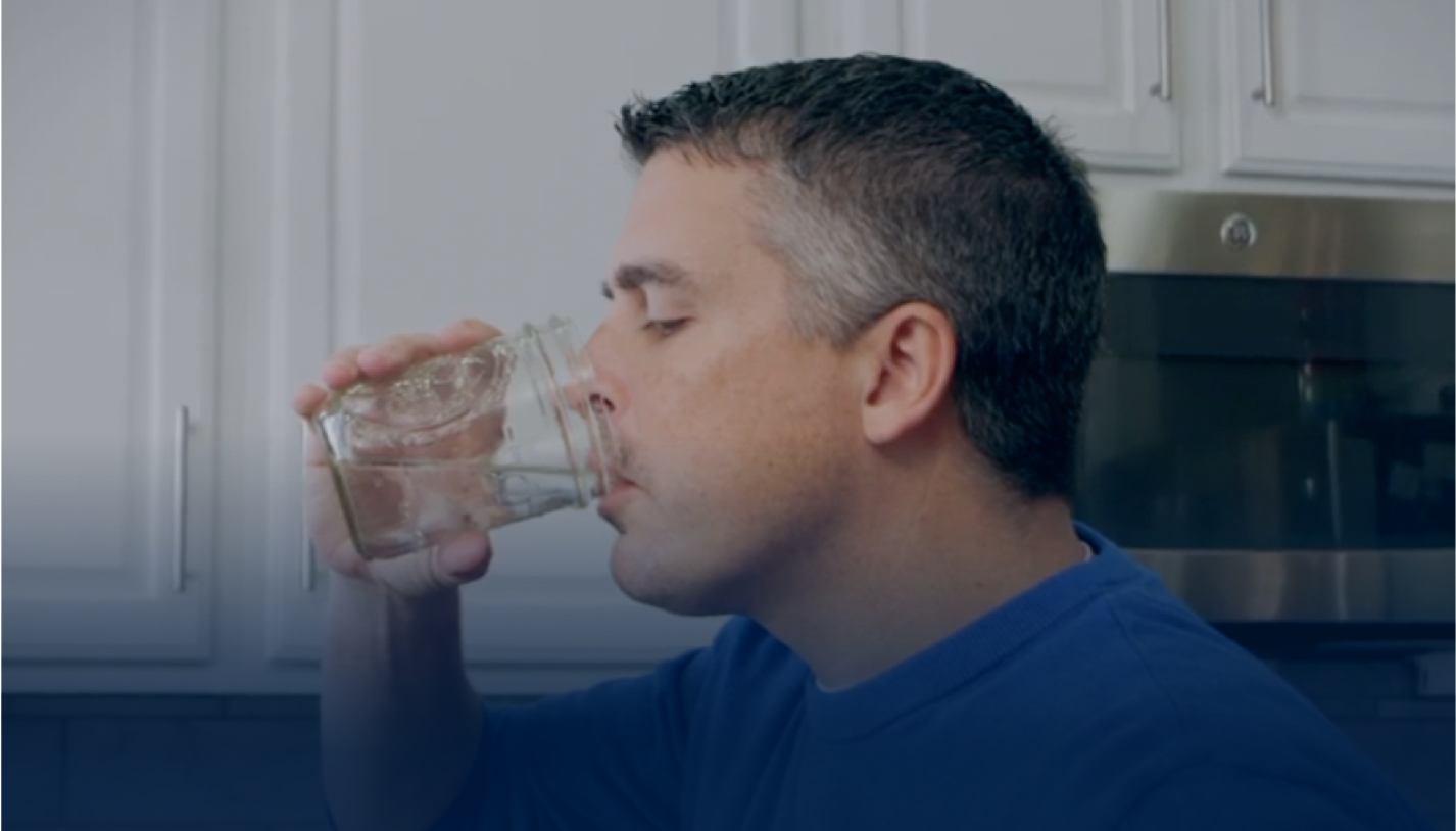 man drinking water out of a glass