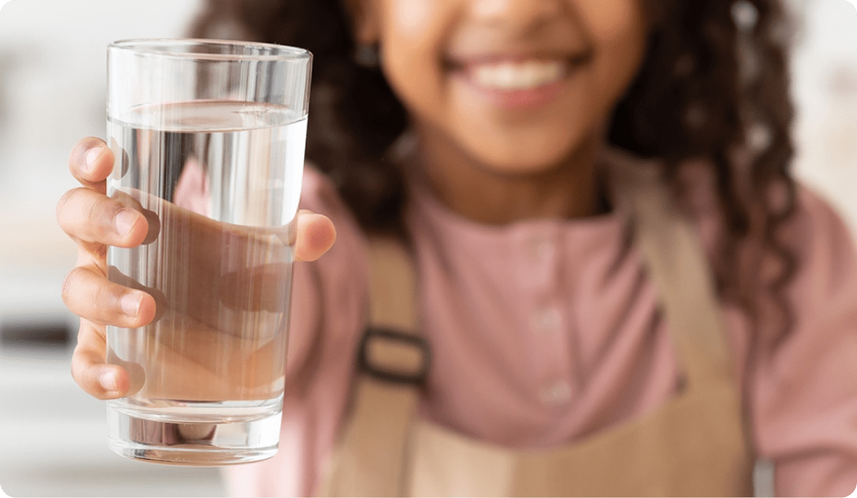 Girl drinking glass of fresh filtered water from dispenser