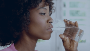 woman drinking water out of a glass